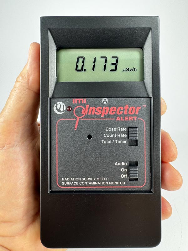 Hand holding an Inspector Alert v2 professional Geiger counter with large easy to read LCD display. Firefighters and first responders like the tactile slide switches which are easy to use with safety gloves on